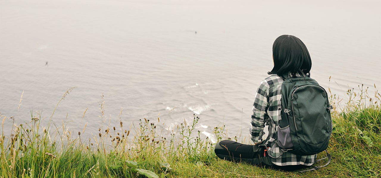 woman sitting at the edge of a lake
