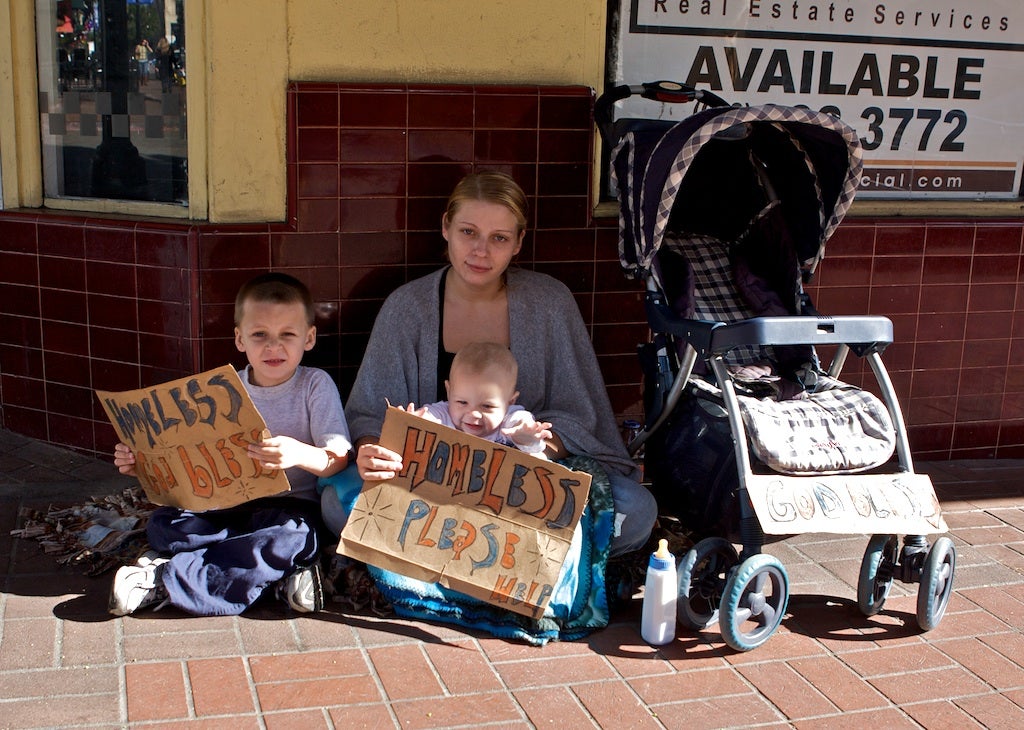 homeless woman with two children holding signs