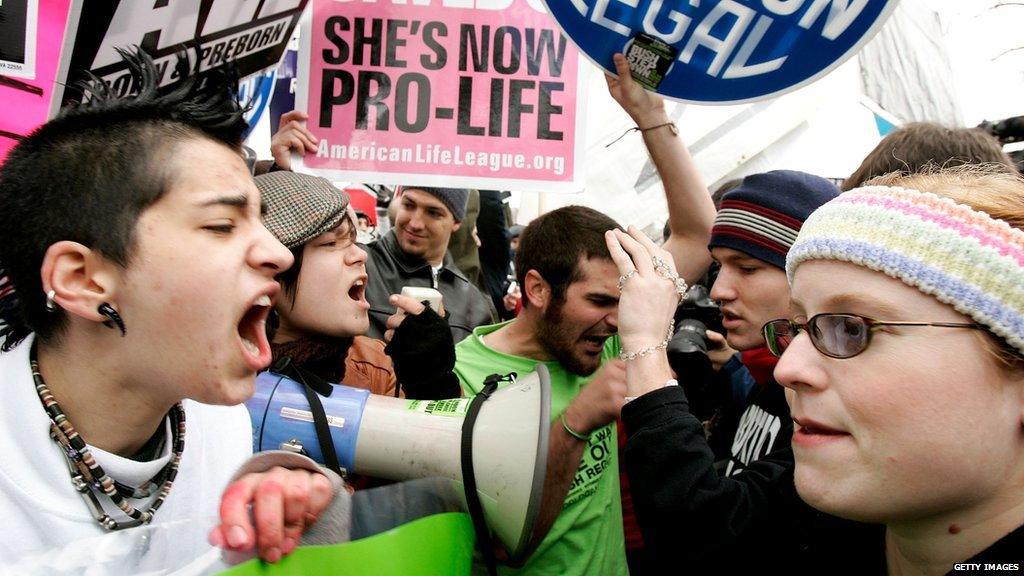 two women yelling at each other over a protest line