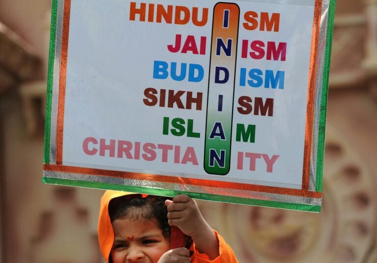 Indian woman holding a sign reflecting various religious traditions practiced in India
