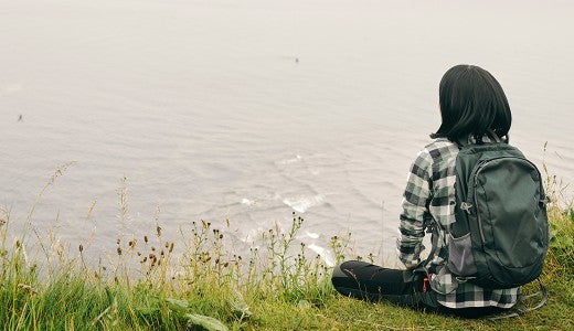 woman sitting at the edge of a lake